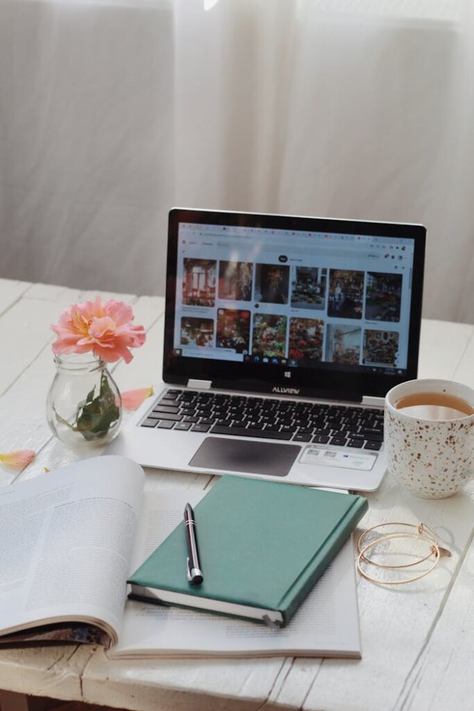 pexels-photo-12815224 A laptop with open planner and coffee cup on a white desk, creating a cozy workspace.